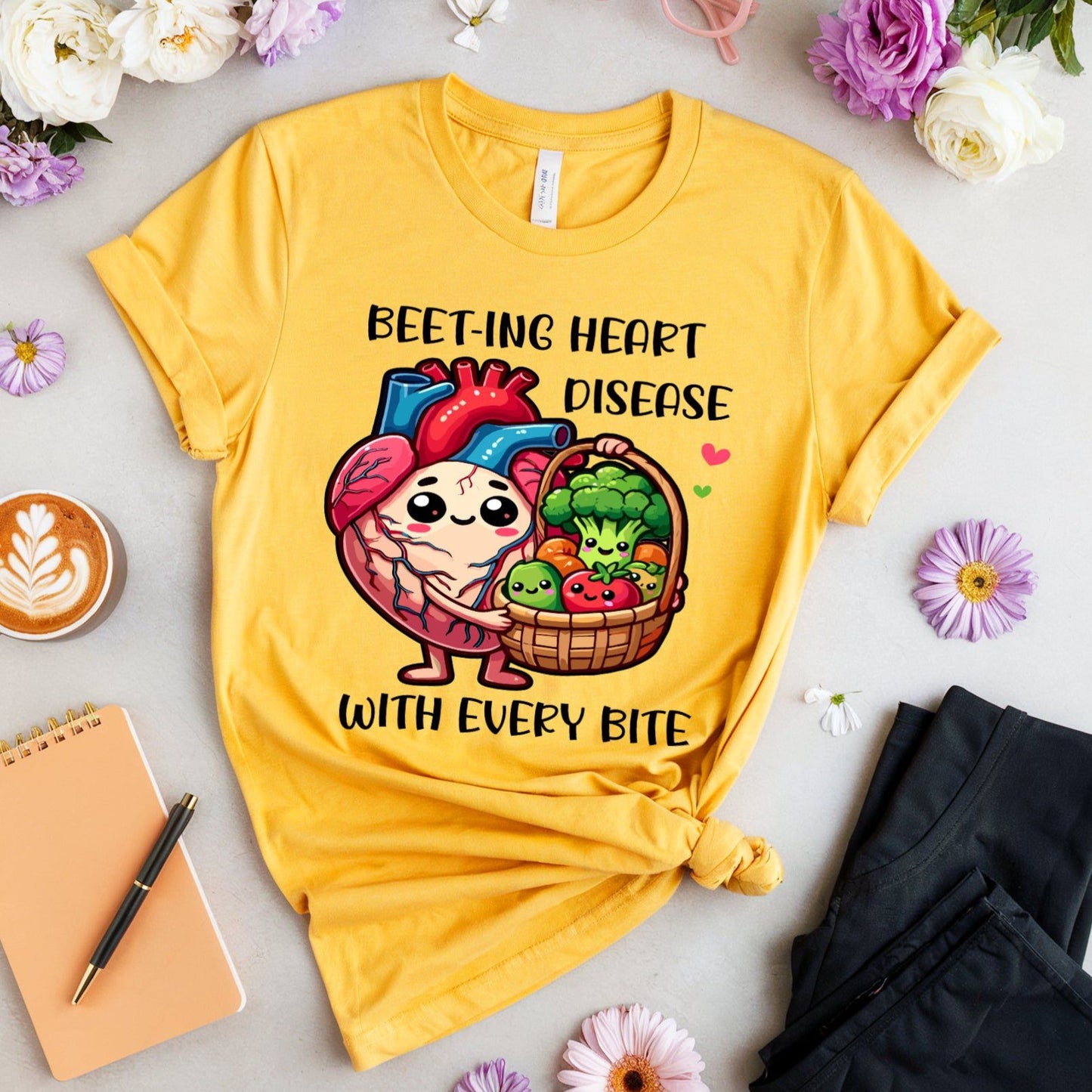 Yellow t-shirt with cartoon design and text on a light surface with flowers and a cup.