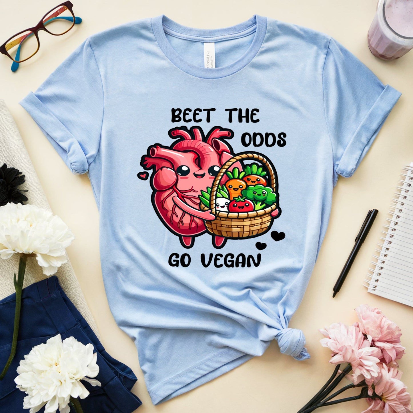 Light blue t-shirt for cardiology with a graphic design and text on a table with flowers and glasses.