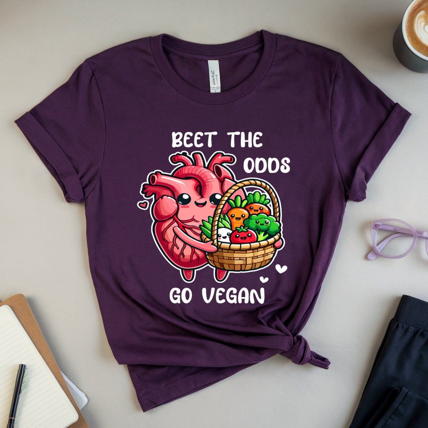 Purple t-shirt for cardiology with a heart design and text on a table with a cup of coffee, glasses, and books.