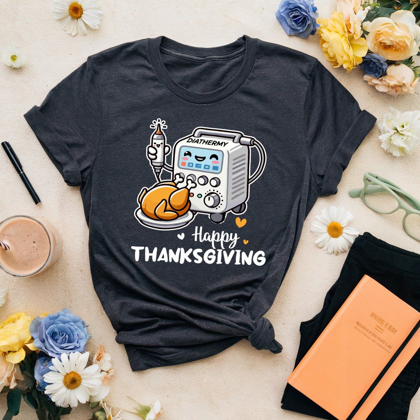 Black t-shirt with 'Happy Thanksgiving' design for OR/Theatre crew on a table with flowers and a notebook.