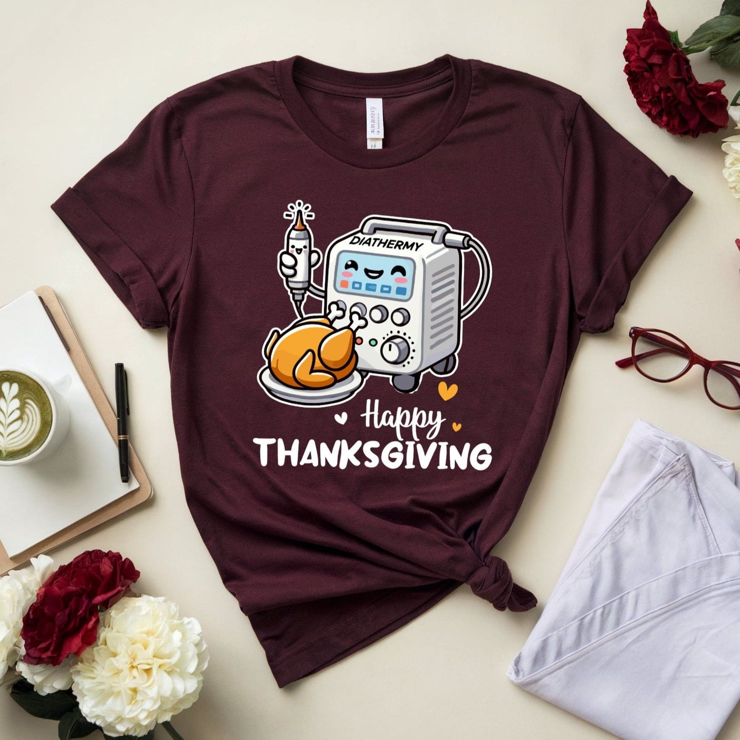 Maroon t-shirt with Thanksgiving graphic for OR/Theatre crew on a table with flowers and glasses