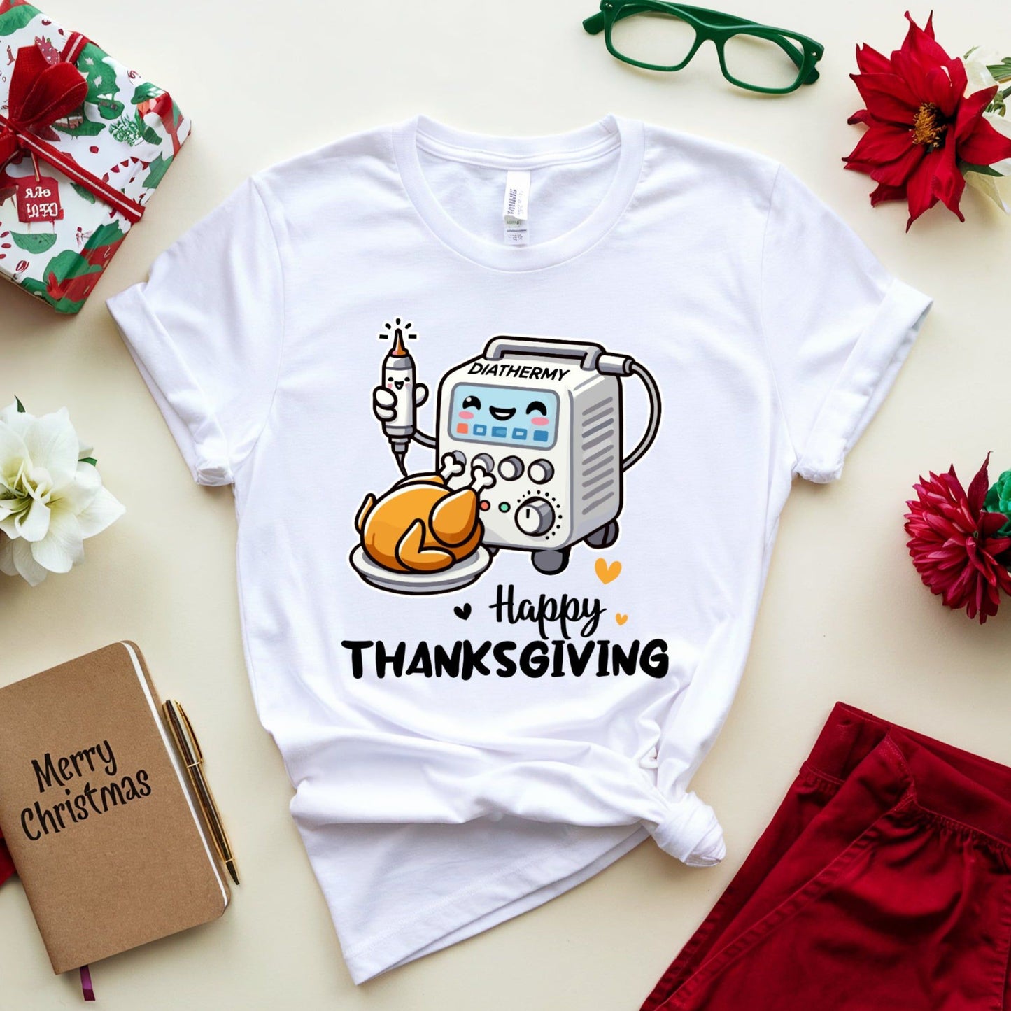 White t-shirt with Thanksgiving design for OR/Theatre crew on a table with Christmas items.