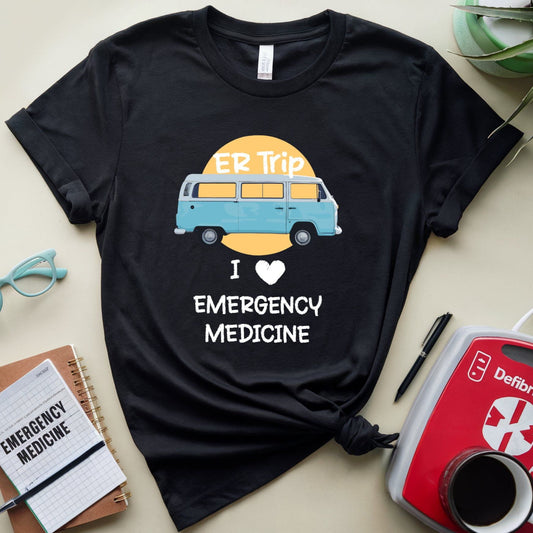 Black t-shirt with a graphic of a van and text 'I love emergency medicine' on a beige surface with accessories.