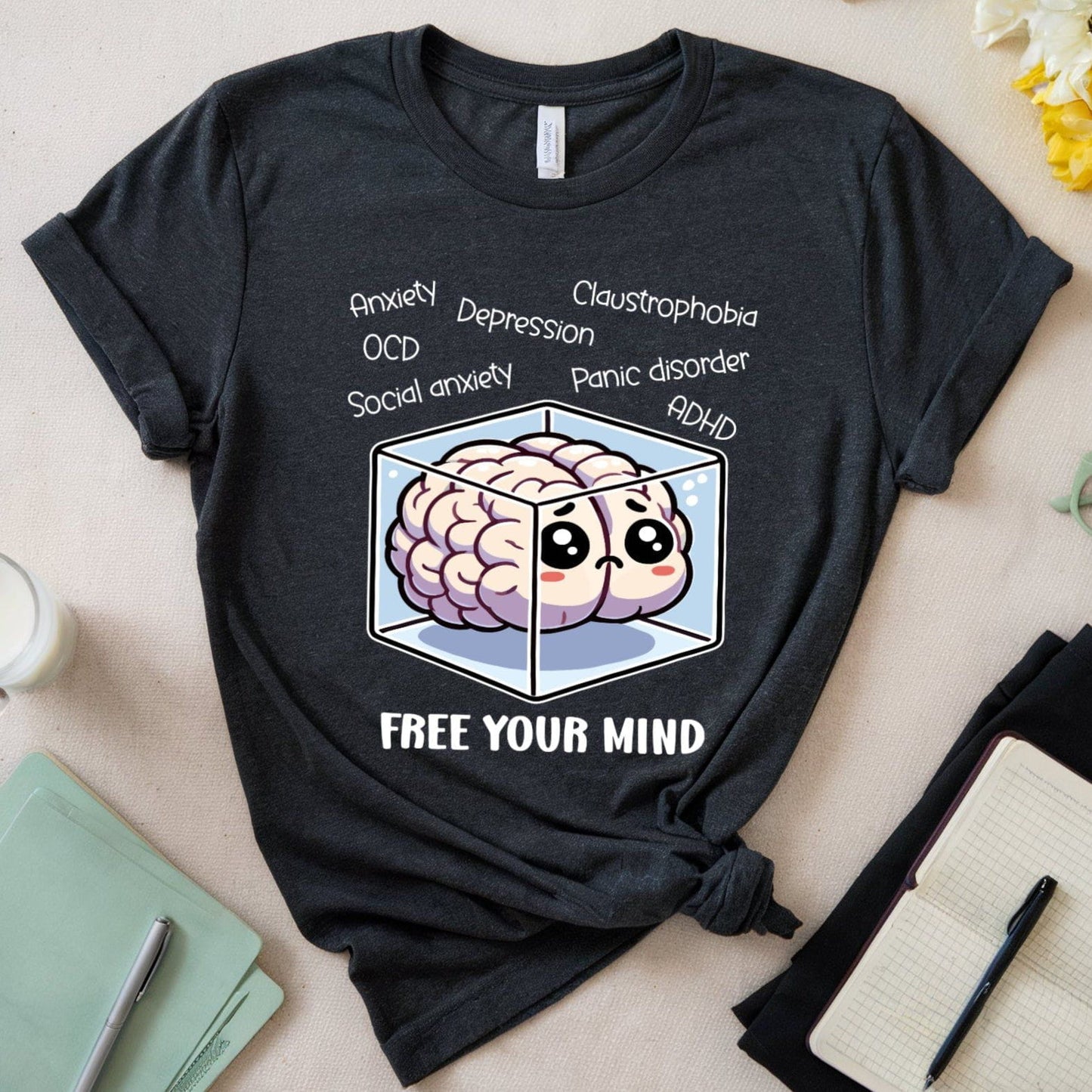 Black t-shirt with a brain graphic and text on a table with stationery items