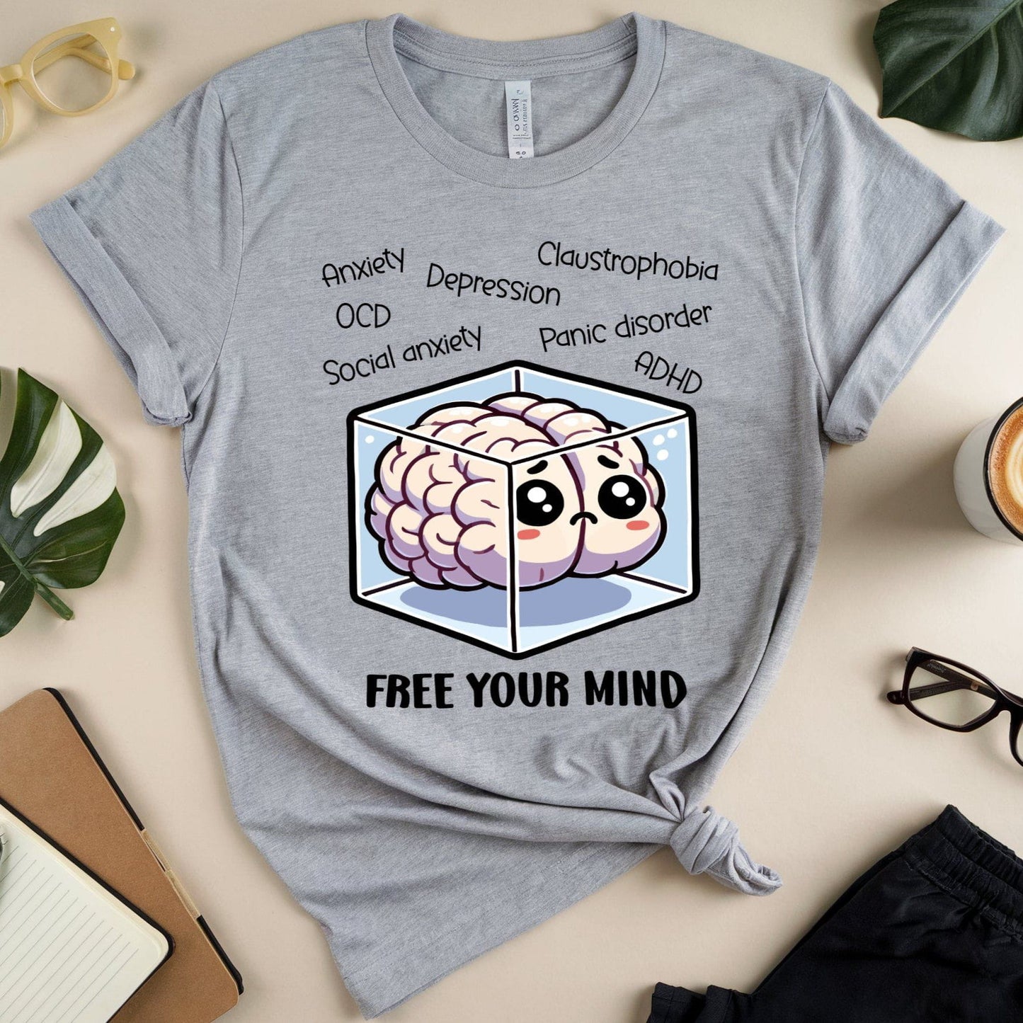 Gray t-shirt with brain graphic and text on a table with stationery items