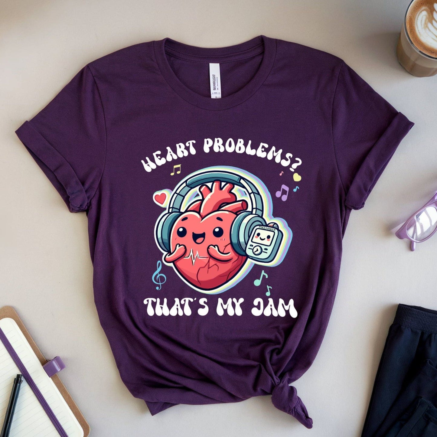 Purple t-shirt with heart graphic and text on a light surface with accessories.