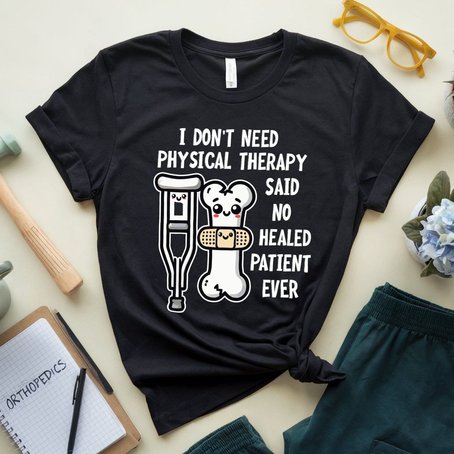 Black t-shirt for orthopedics with humorous text and graphics on a light surface with accessories.