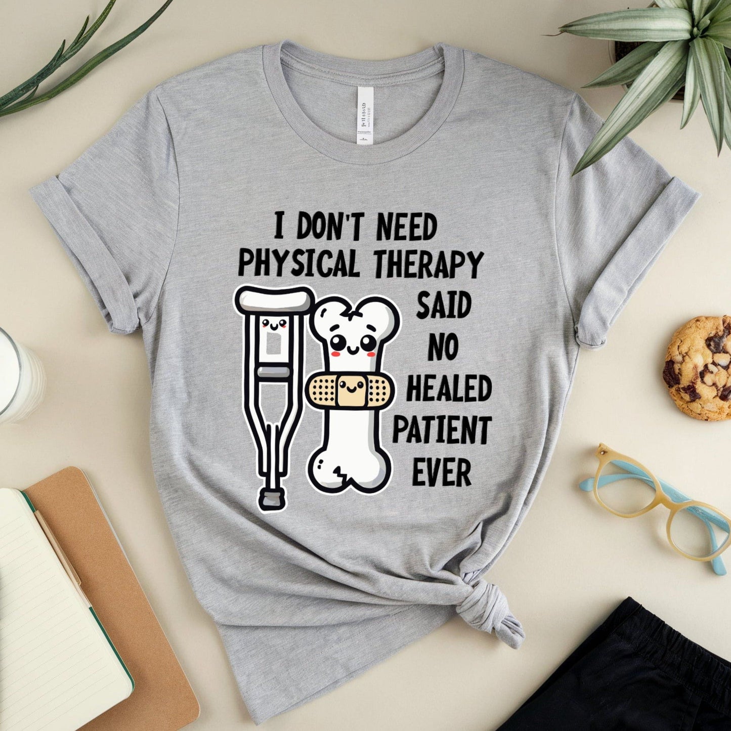 Gray t-shirt for orthopedics with humorous graphic and text on a table with stationery items