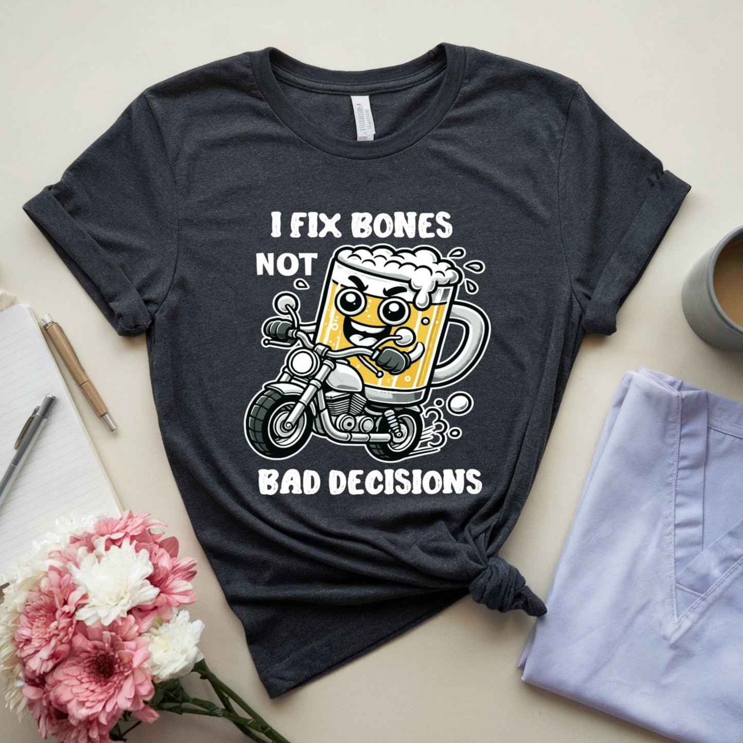 Dark gray t-shirt for orthopedics with a graphic design and text on a light surface with a mug, flowers, and jeans.