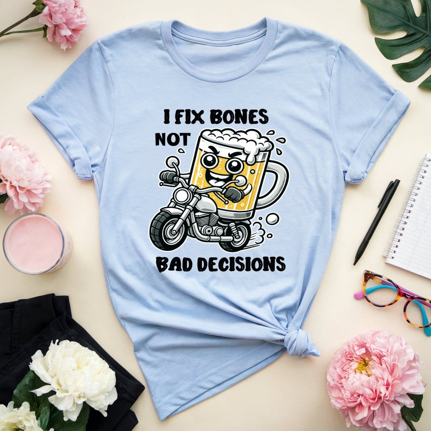 Light blue t-shirt orthopedics with a graphic design and text on a table with flowers and stationery.
