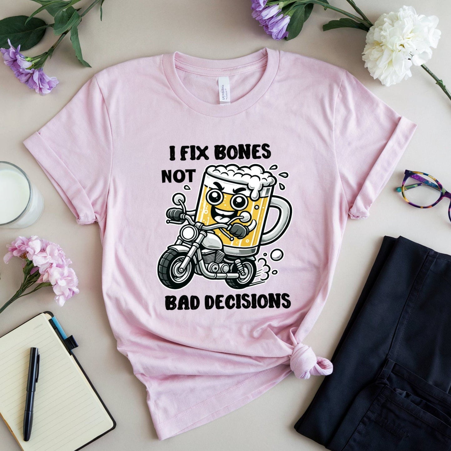 Pink t-shirt for orthopedics with a graphic design and text on a table with flowers and glasses.