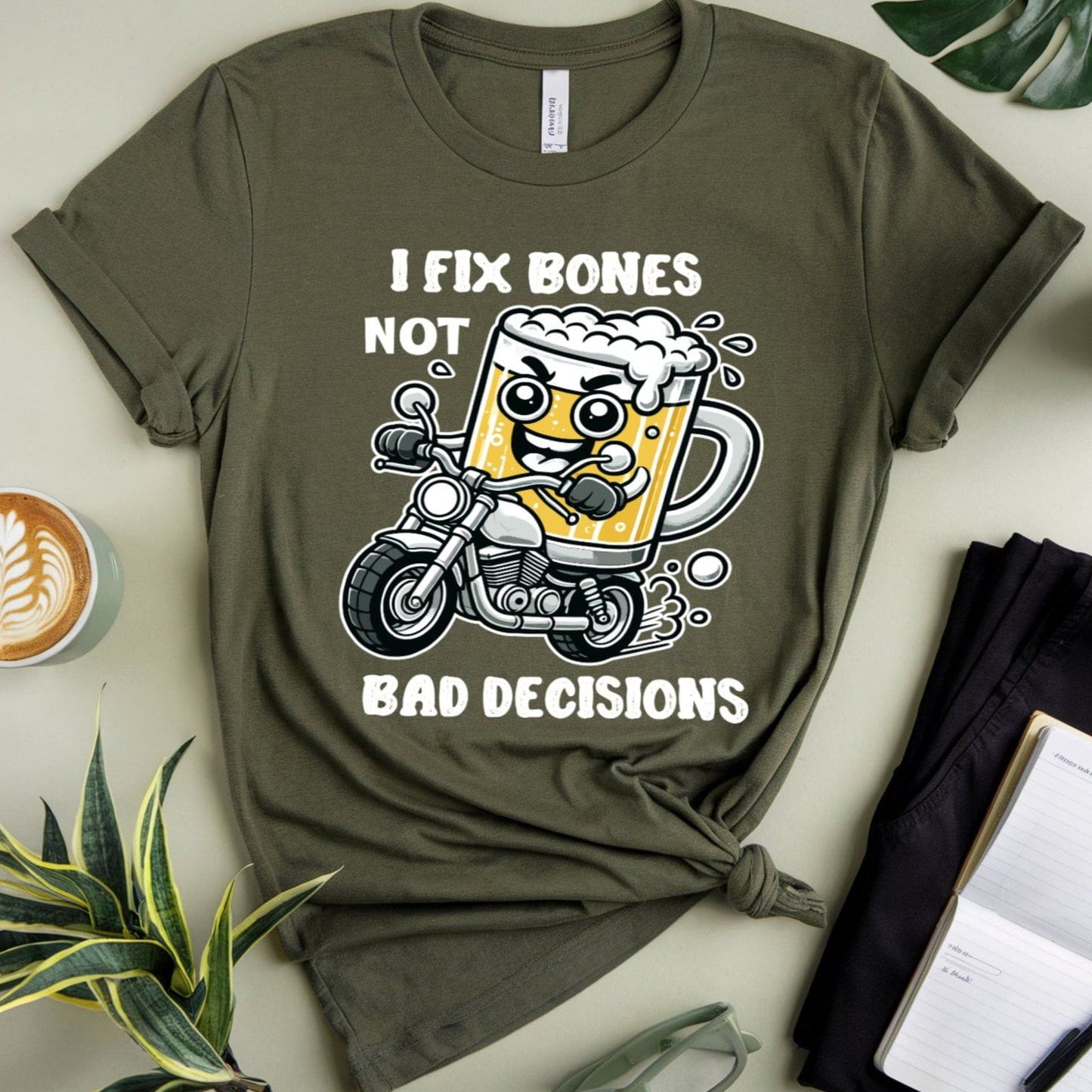 Green t-shirt for orthopedics with a graphic design on a light surface with plants and a coffee cup.