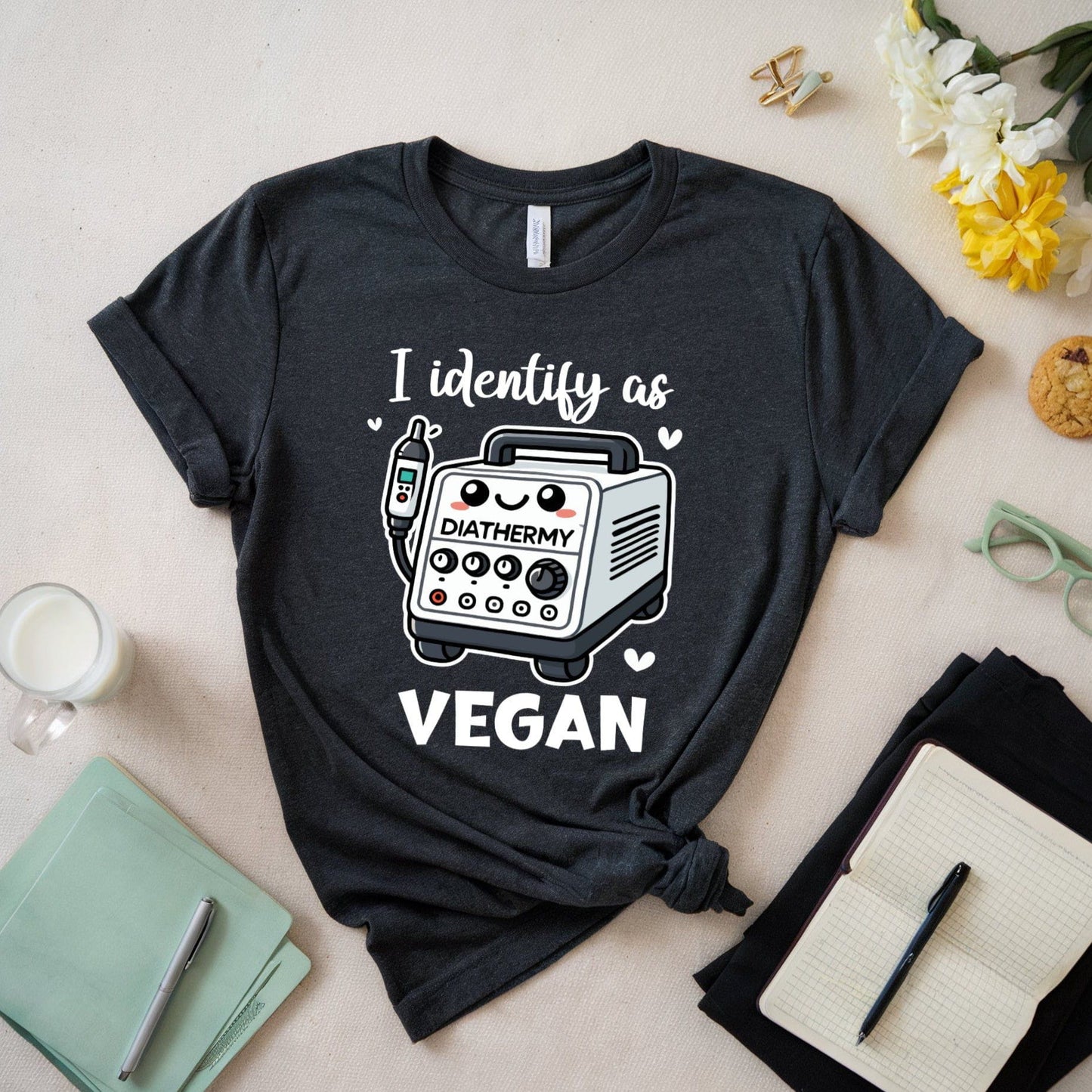 Black t-shirt with a graphic and text 'I identify as vegan' on a light surface with accessories.