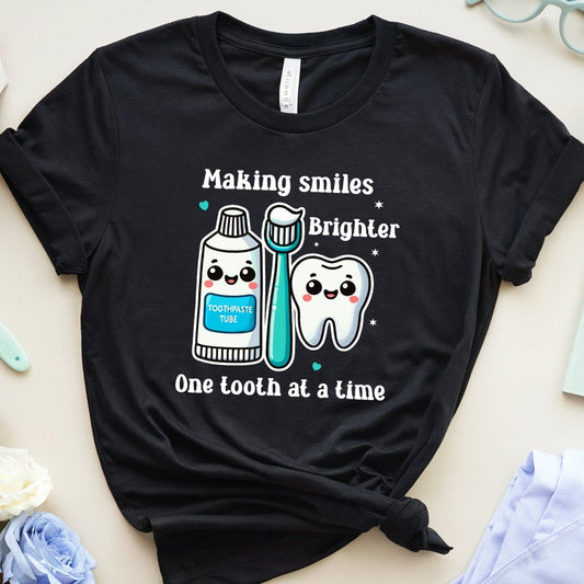 Black t-shirt with dental-themed design on a light surface with dental-themed items.