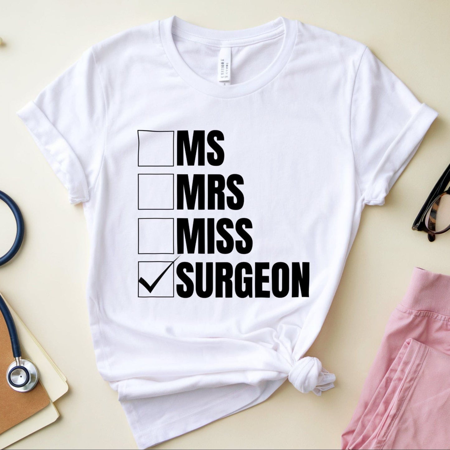 White t-shirt with humorous text design on a light surface with medical-themed items.