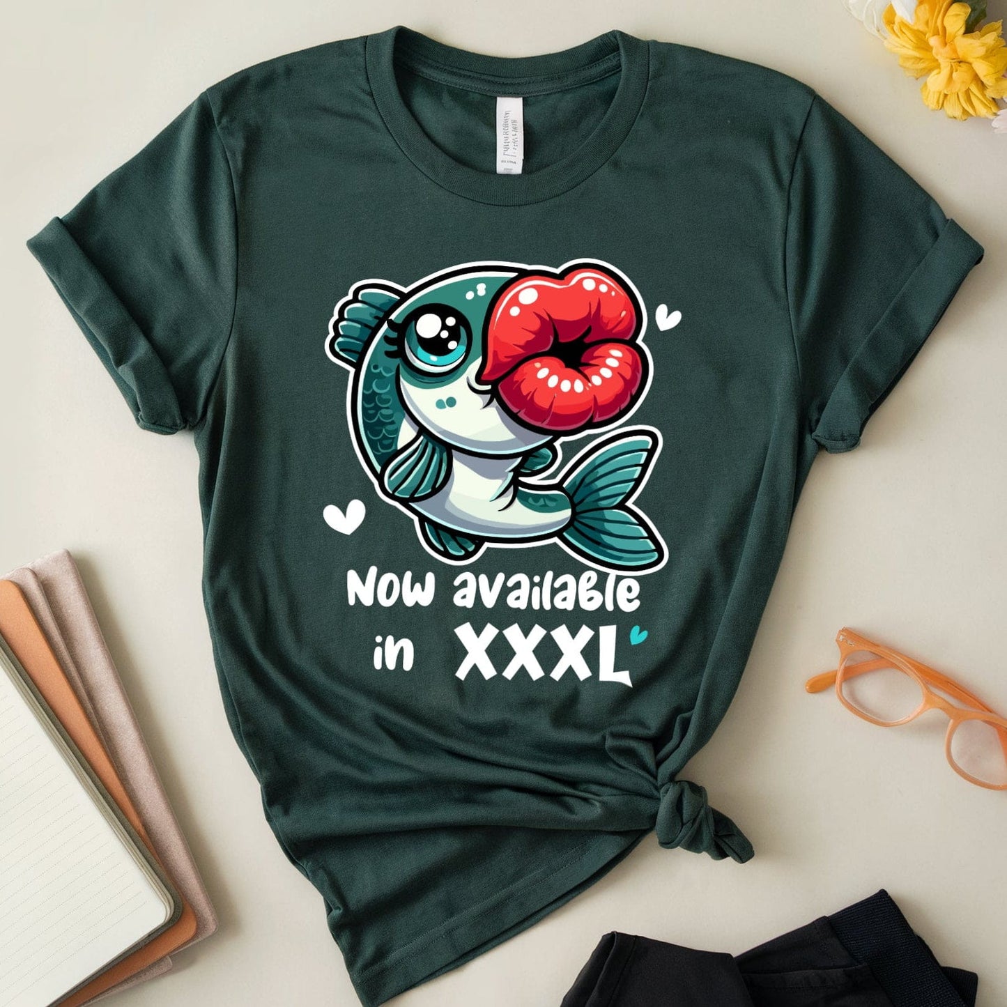 Green t-shirt with a fish graphic and text on a light surface with flowers and glasses.