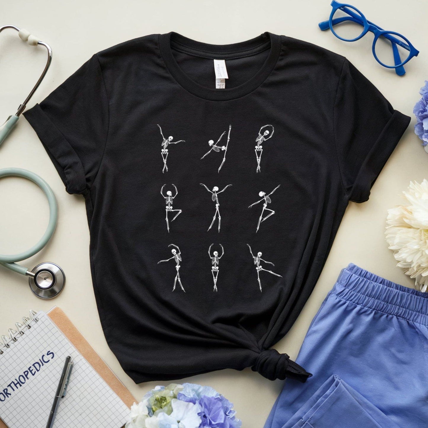 Black t-shirt for orthopedics with white graphic design on a light surface with medical-themed items.