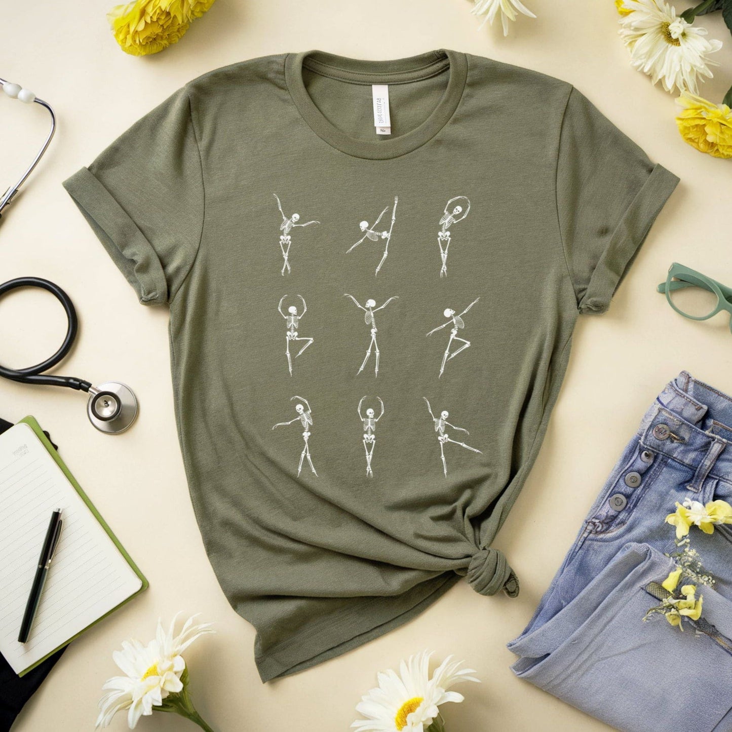 Green t-shirt with skeleton designs for orthopedics on a light surface with flowers and jeans.