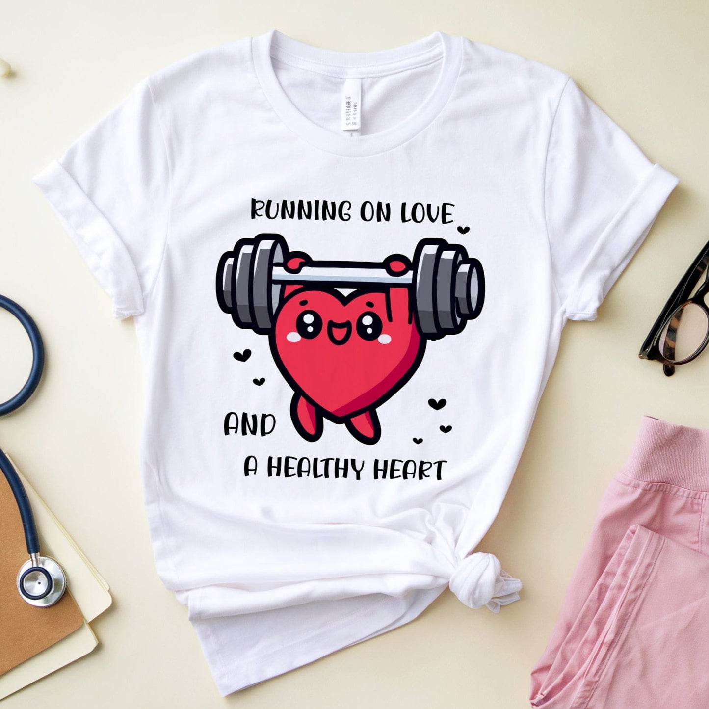 White t-shirt with a heart design lifting weights and text 'Running on love and a healthy heart' on a light surface.