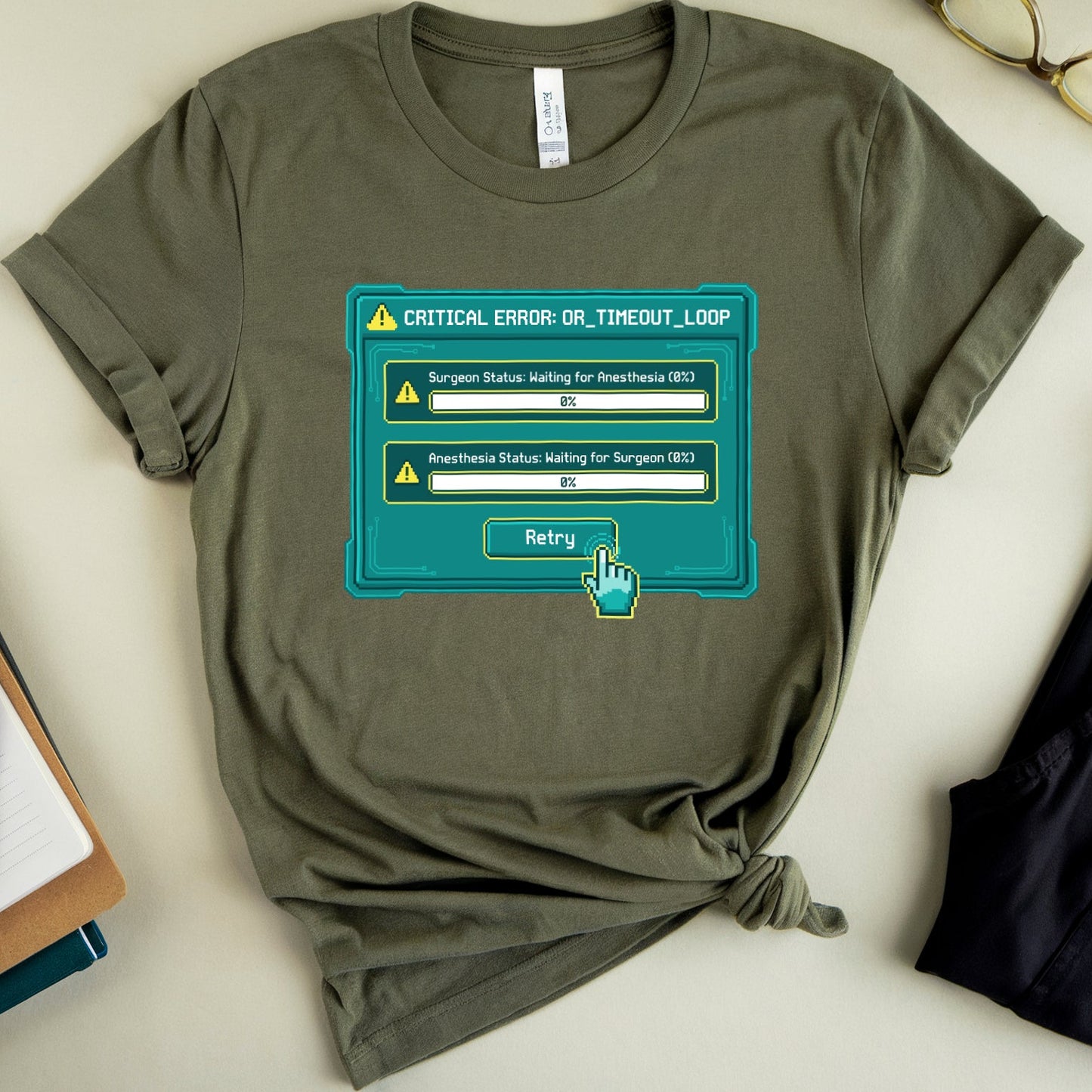 Green t-shirt with a computer error graphic on a white surface with glasses and a book.