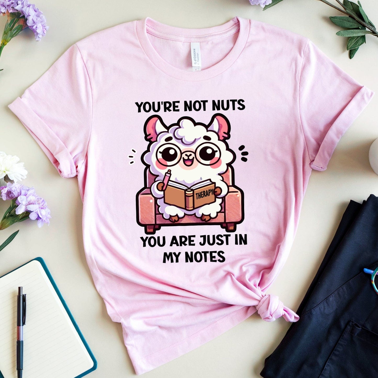 Pink t-shirt with cartoon character and text on a table with flowers and a cup of coffee.