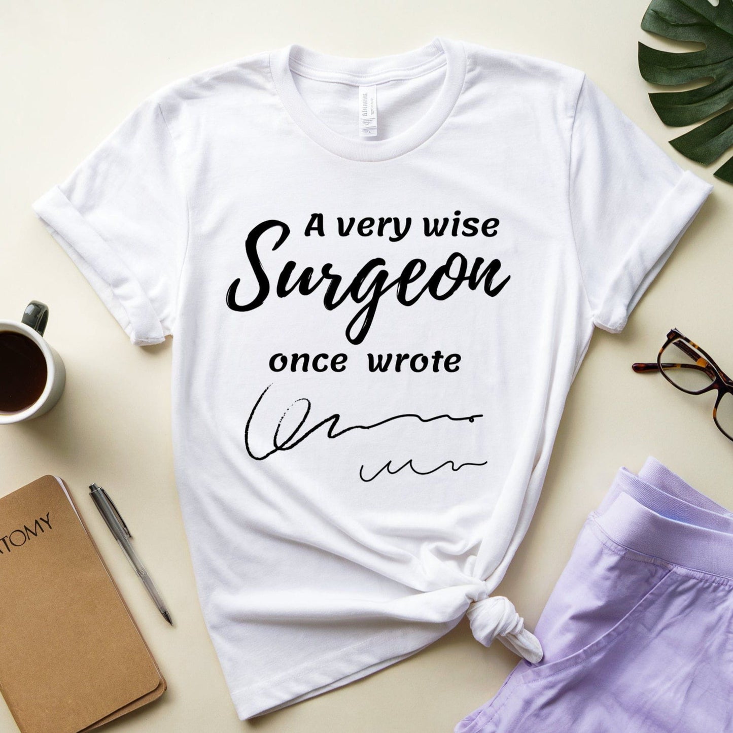 White t-shirt  for surgeons with humorous text design on a light surface with accessories.