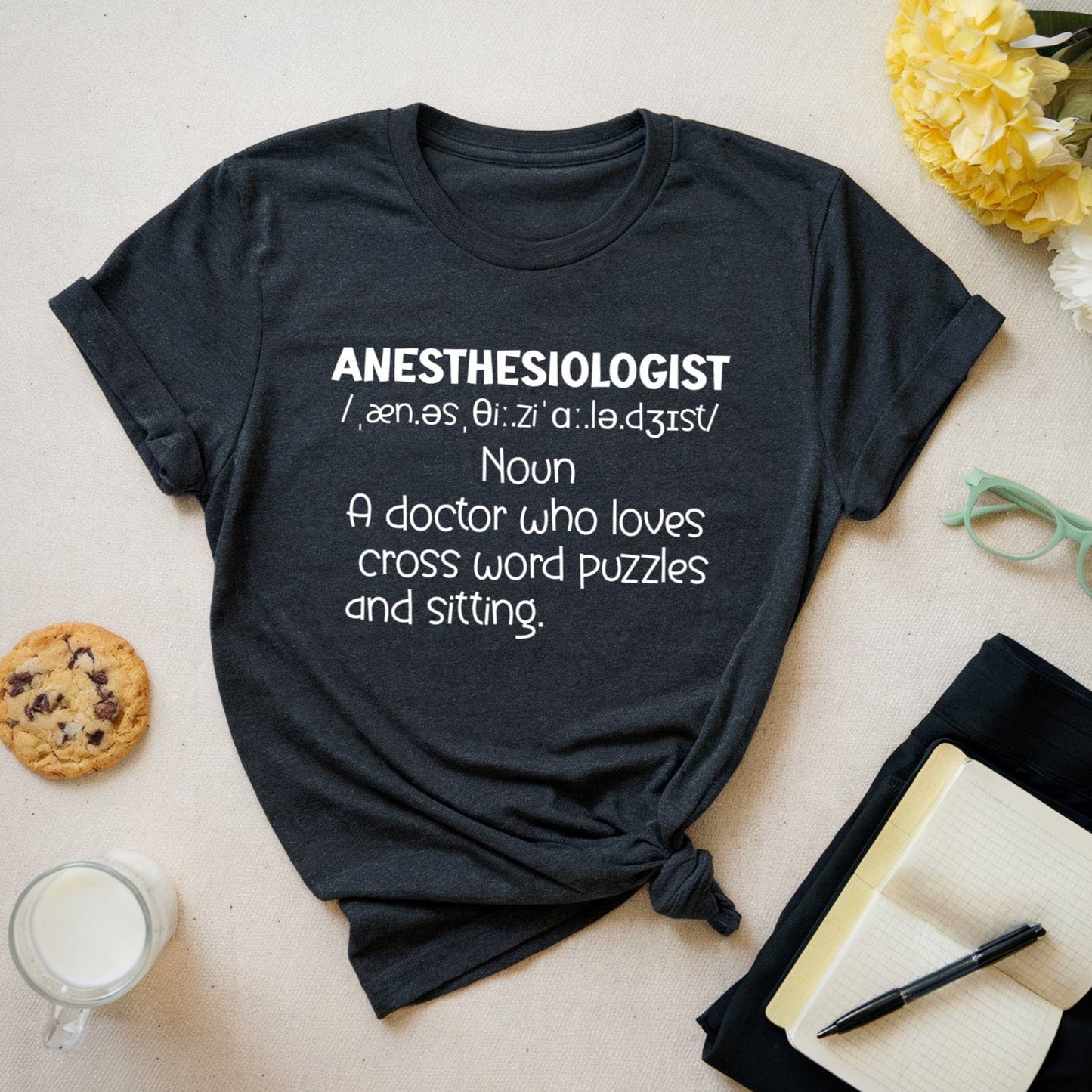Black t-shirt with 'Anesthesiologist' definition text on a light surface with snacks and glasses.