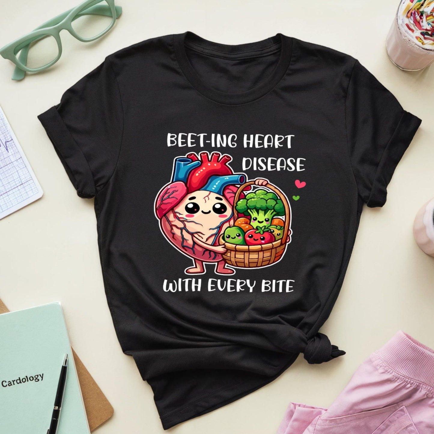 Black t-shirt with a cartoon heart and vegetables design on a table with accessories.