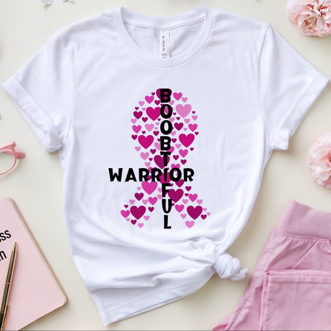 White t-shirt with pink ribbon design, pink pants, glasses, and flowers on a light background