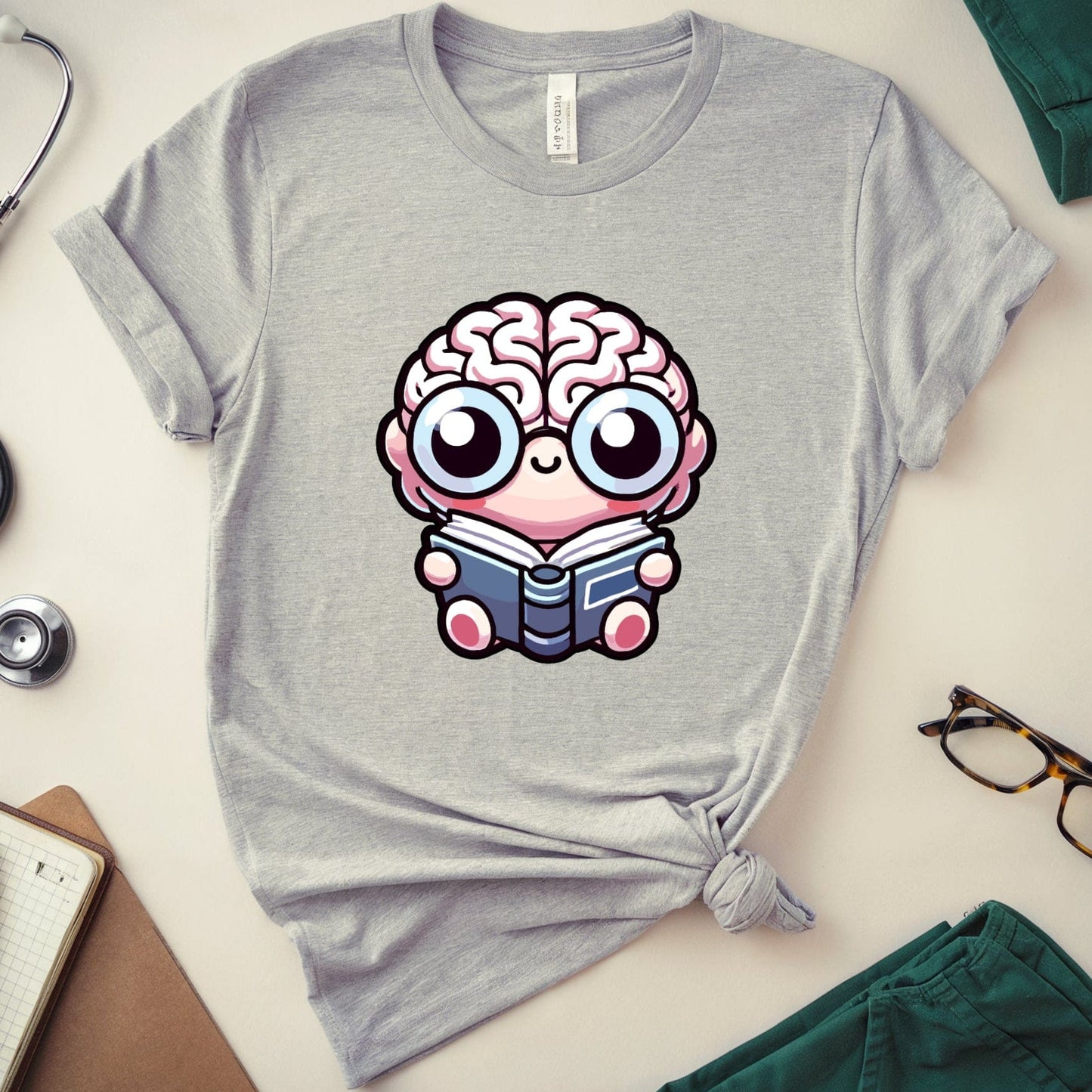 Gray t-shirt with a cartoon brain design on a white surface with accessories.