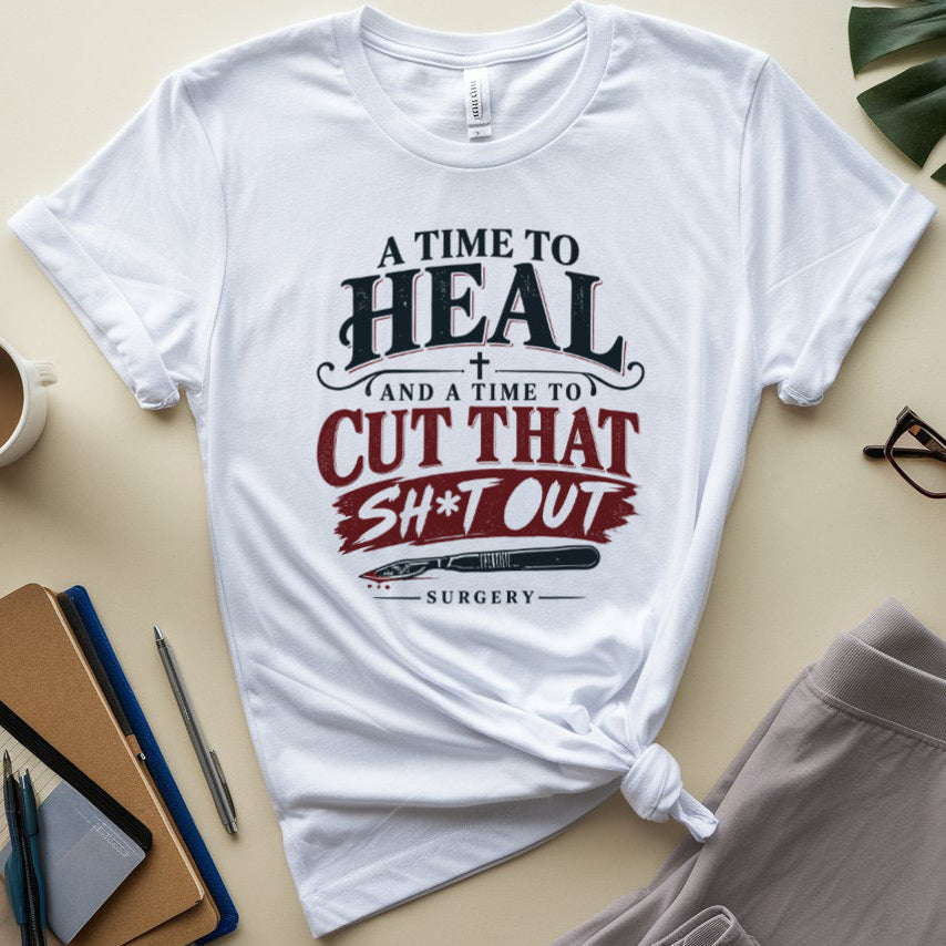 A white graphic t-shirt with a medical-themed slogan, styled in a flat lay with a coffee mug, notebook, eyeglasses, and shorts on a beige background.