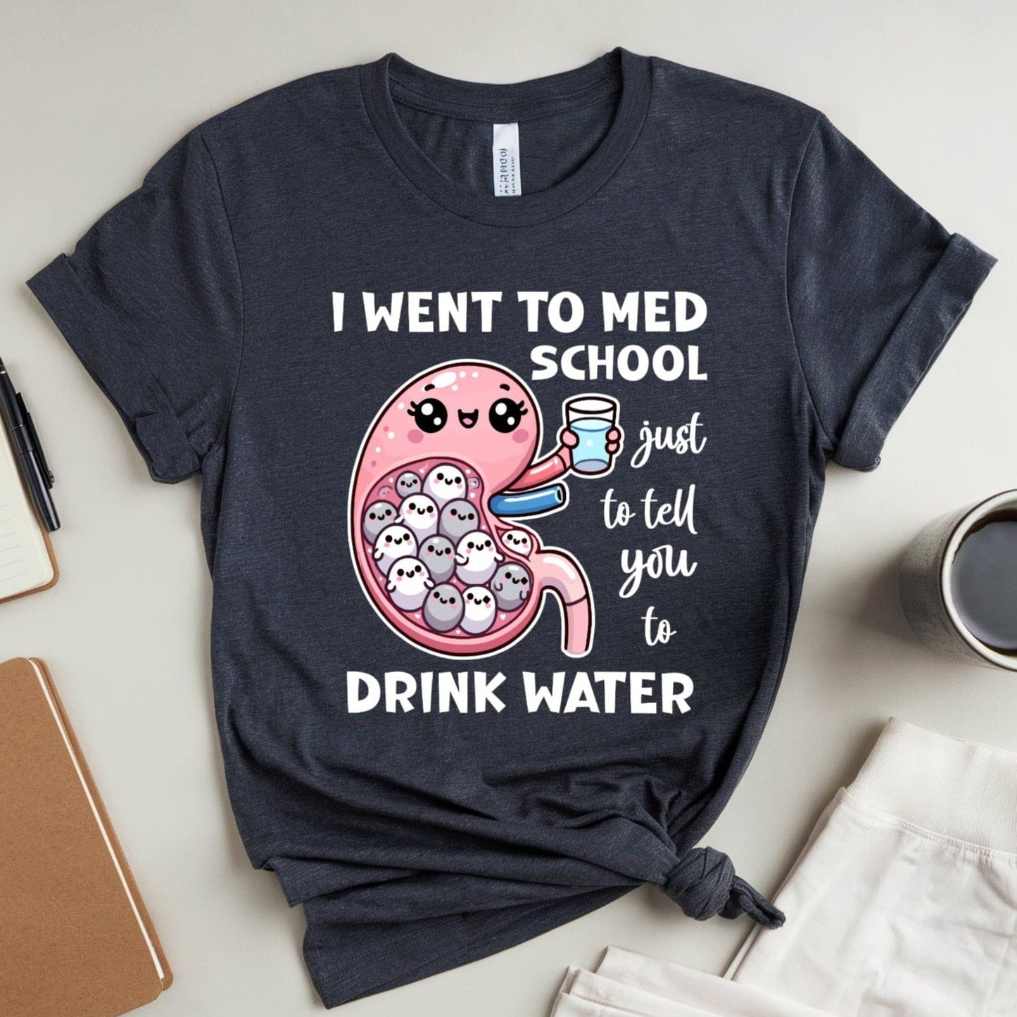 Navy blue t-shirt with a graphic design and text on a light surface with stationery items.
