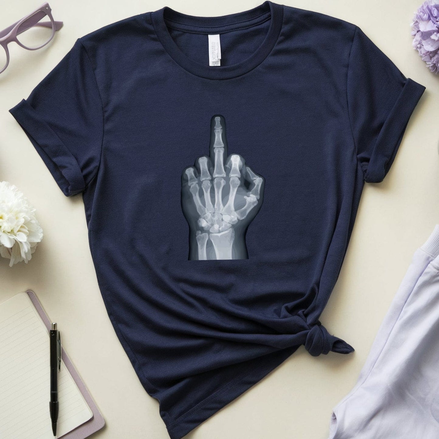 Navy blue t-shirt with a graphic design on a light surface with accessories around