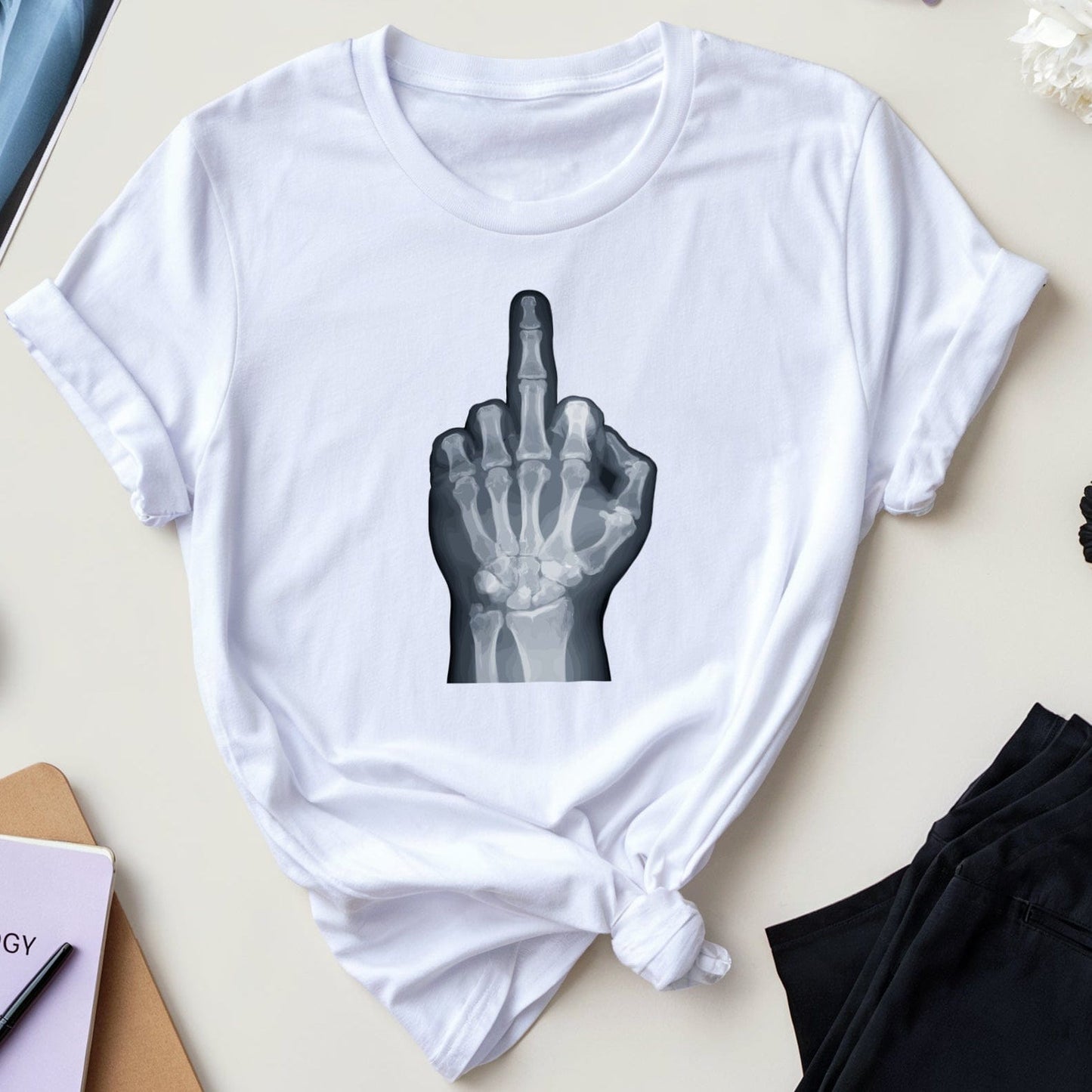 White t-shirt with x-ray design of a hand giving the middle finger on a table with medical books and flowers.