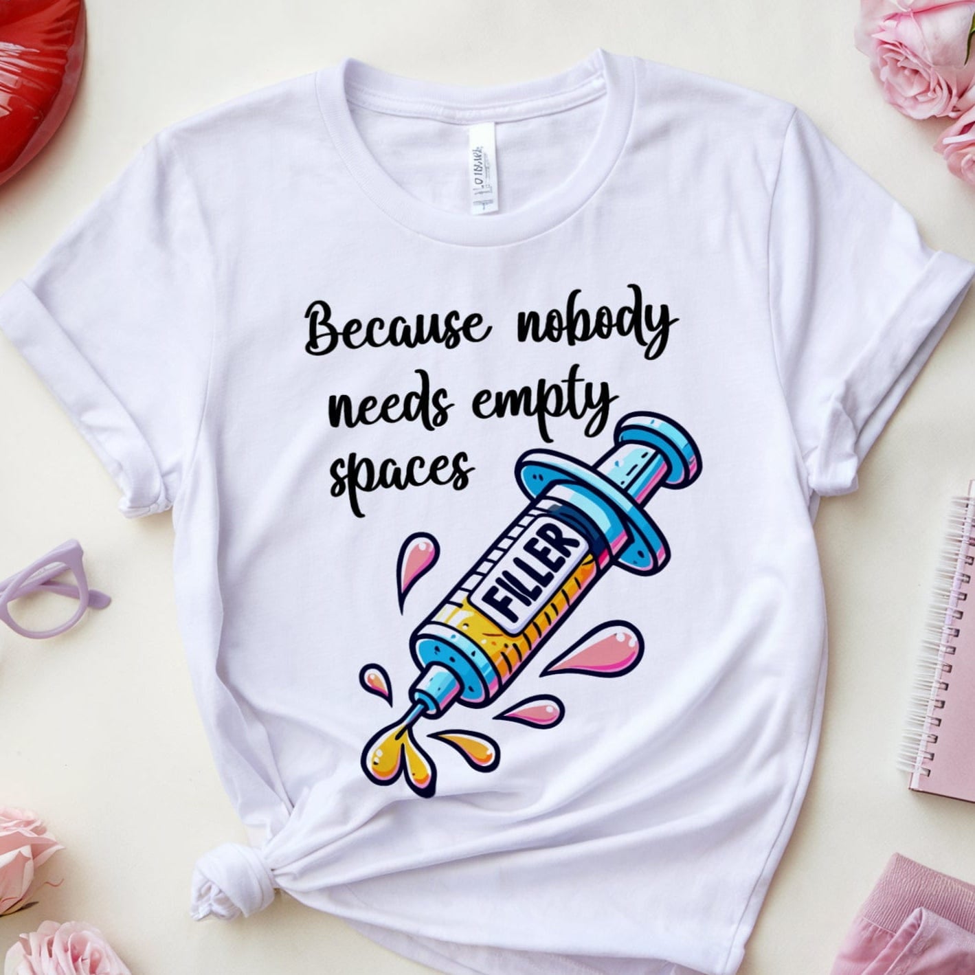 White t-shirt with colorful graphic and text on a light surface with accessories.