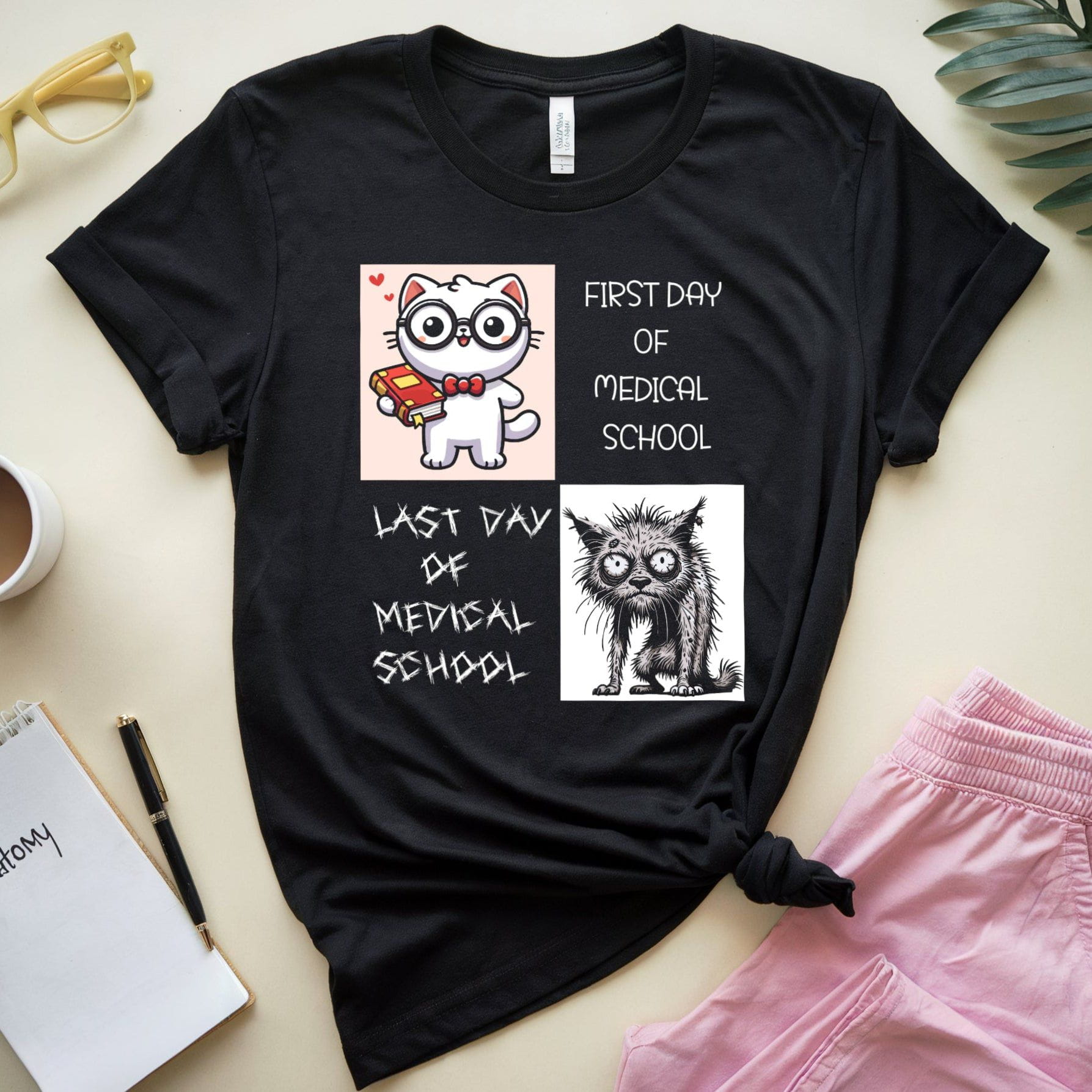 Black t-shirt with cat illustrations and text on a light surface with accessories.