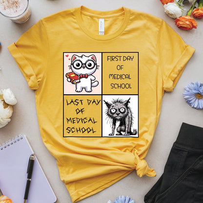 Yellow t-shirt with a graphic design of a cat and text about medical school on a light surface.