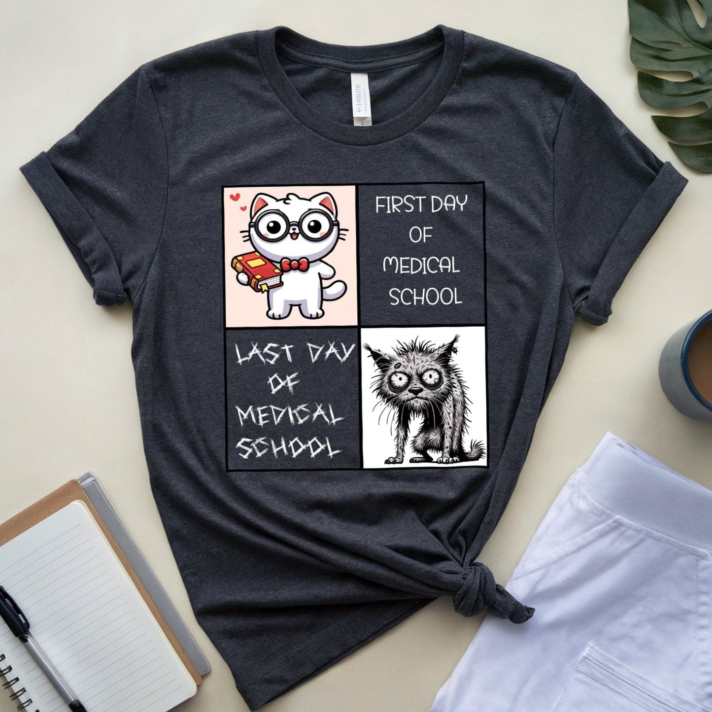 Dark gray t-shirt with cartoon cat illustrations and text on a light surface.