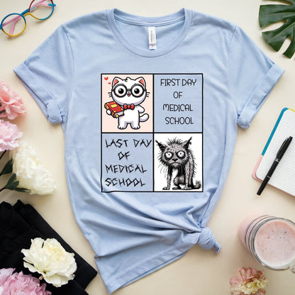 Light blue t-shirt with cartoon cat design on a table with flowers and stationery.