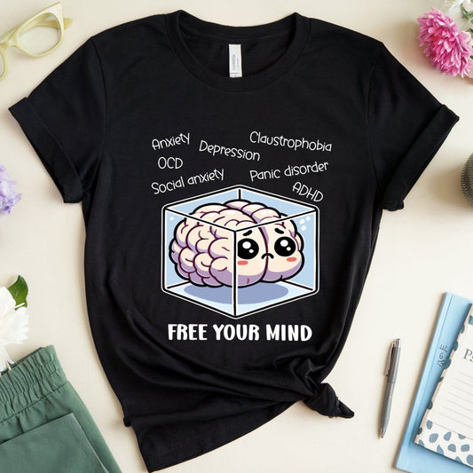 Black t-shirt with brain graphic and text on a light surface with flowers and glasses.