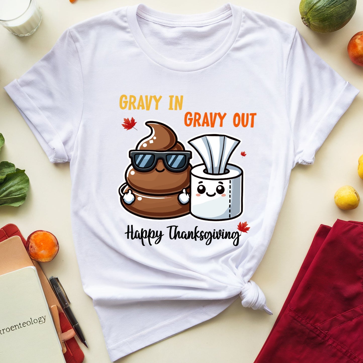 White t-shirt with a humorous Thanksgiving design featuring a cartoon poop and tissue, surrounded by vegetables and a glass of milk.