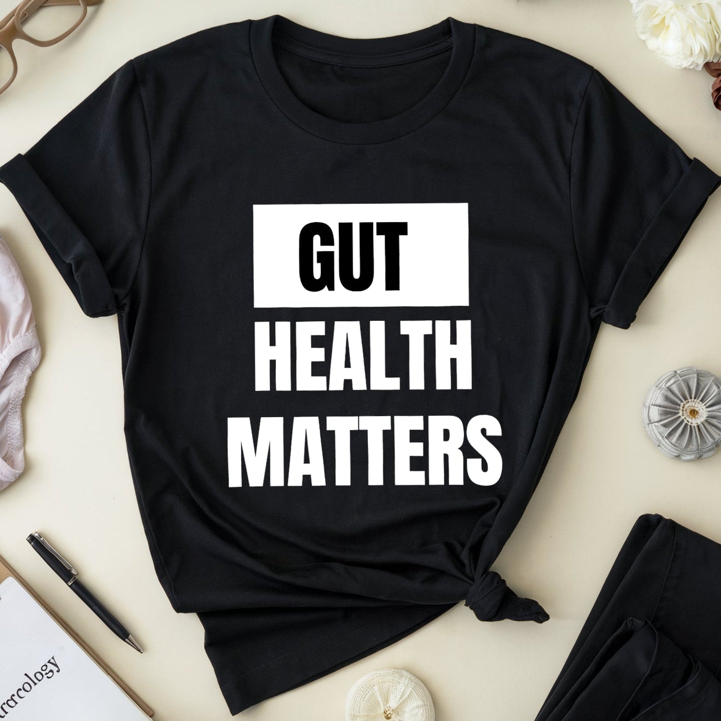 Black t-shirt with 'GUT HEALTH MATTERS' text on a light surface with accessories.