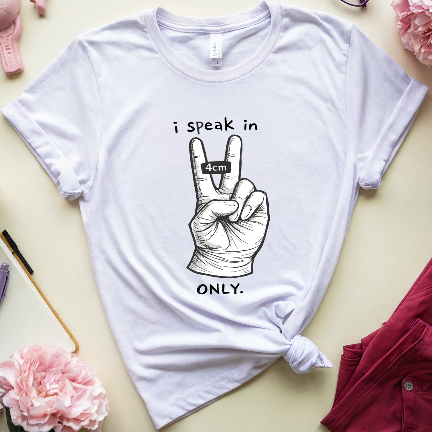White t-shirt with graphic design and text on a table with flowers and glasses