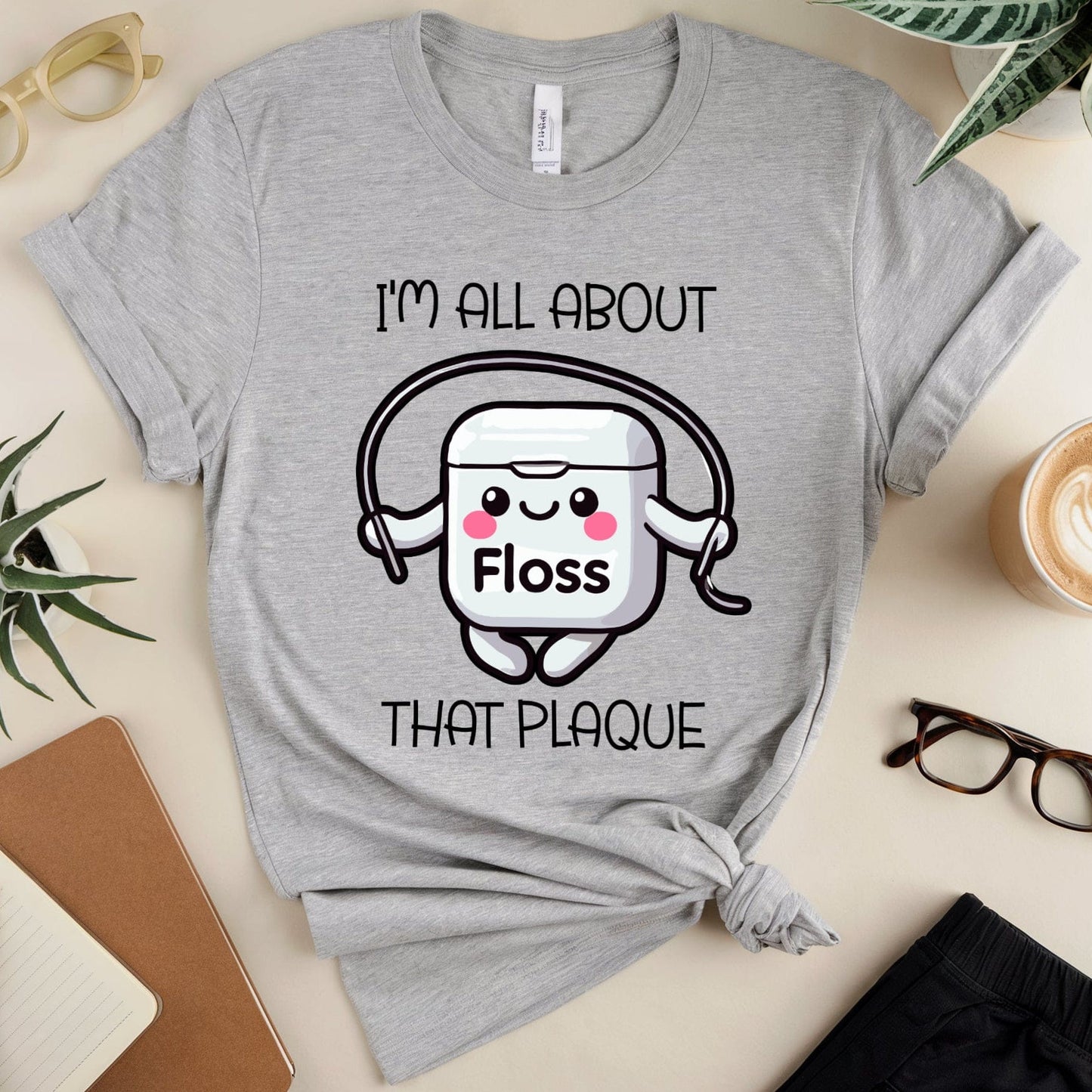 Gray t-shirt with dental-themed graphic and text on a table with accessories