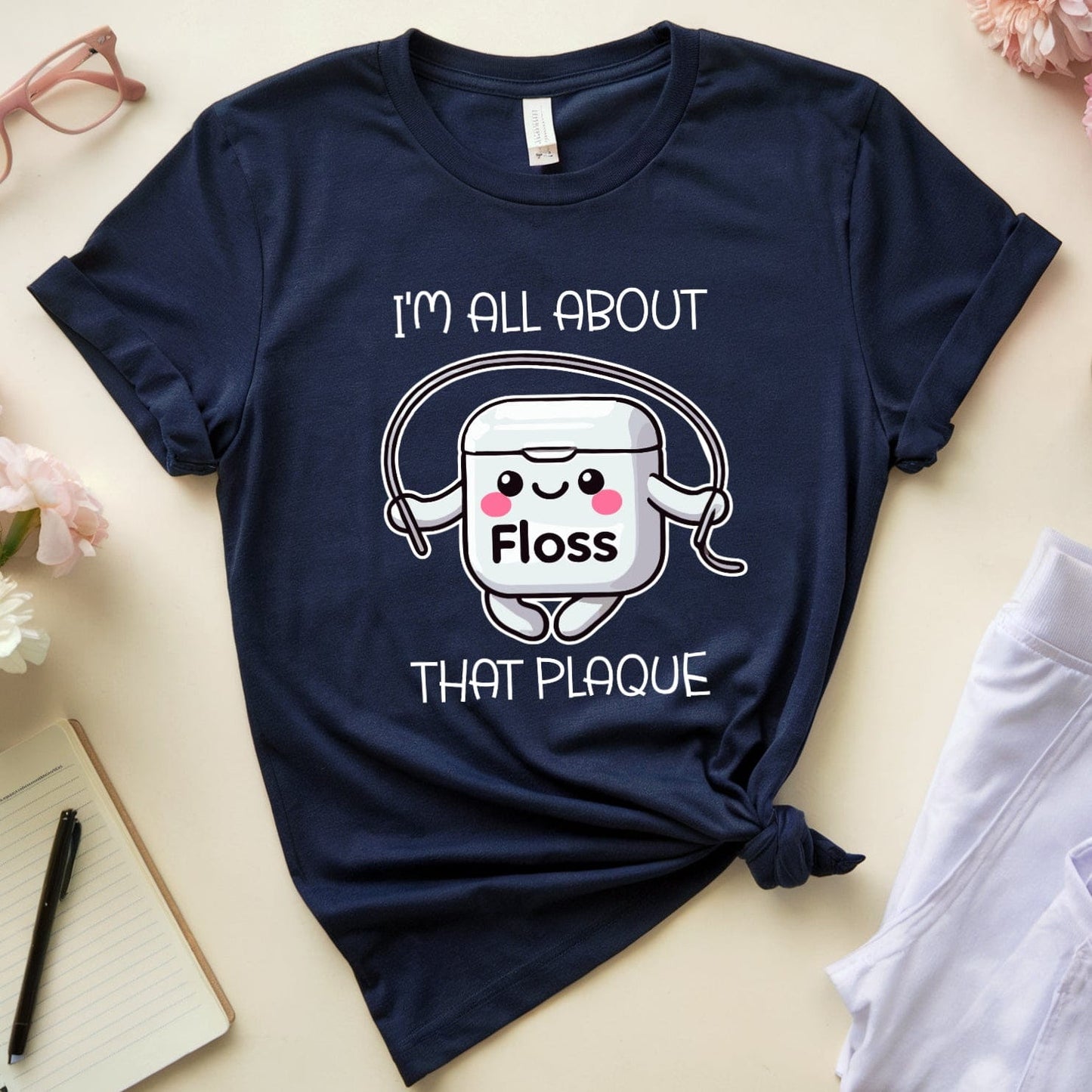 Navy blue t-shirt with dental floss graphic and text on a light surface with flowers and a cup.