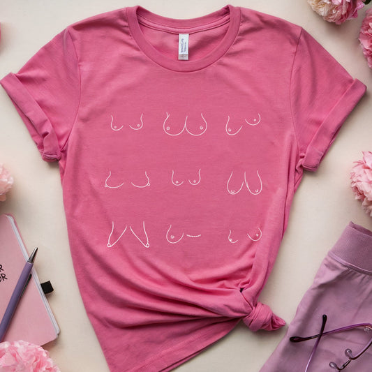 A pink short-sleeve graphic T-shirt with white cursive text reading 'BE YOUR OWN GURU' arranged in rows, styled in a flat lay with pink flowers, a pink ribbon, a notebook, and lavender shorts on a light beige background.