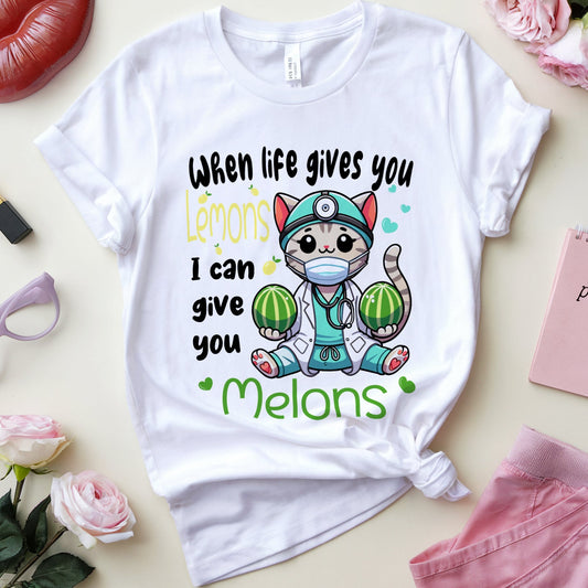 White t-shirt with a graphic design featuring a cat holding watermelons and text on a light surface with accessories around.