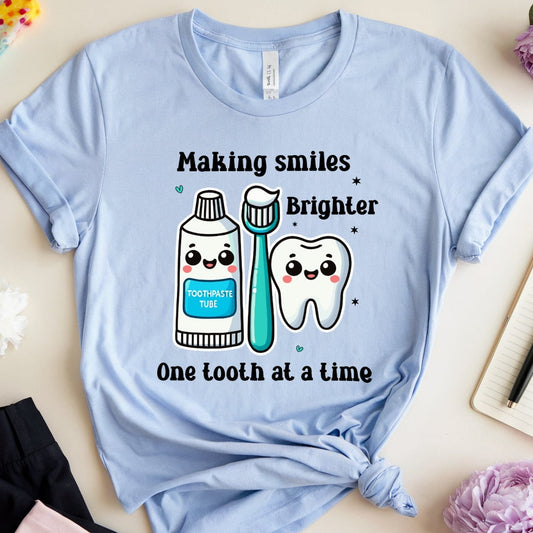 Light blue t-shirt with dental-themed design on a light surface with flowers and stationery.
