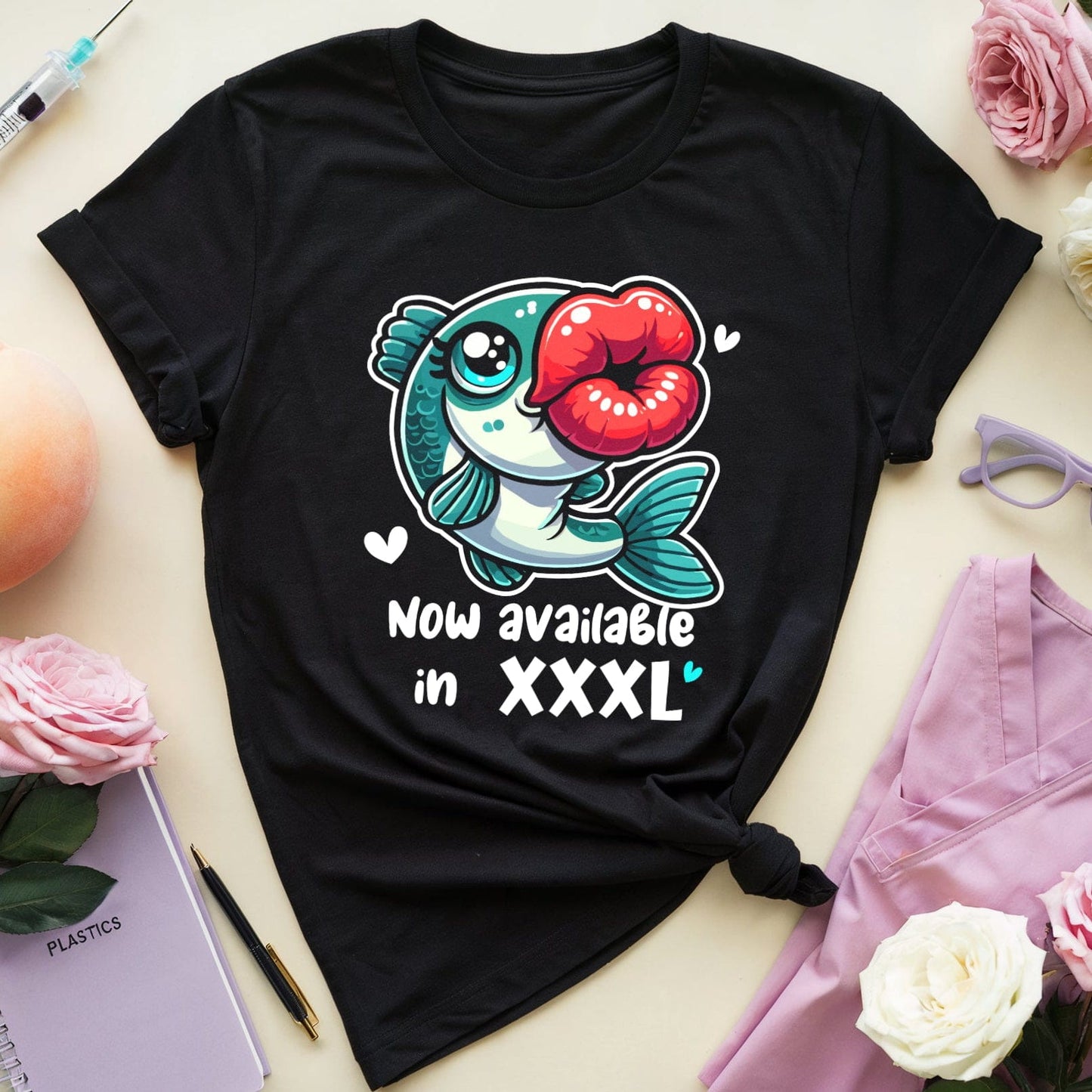 Black t-shirt with a fish graphic and text on a light surface with flowers and sunglasses.