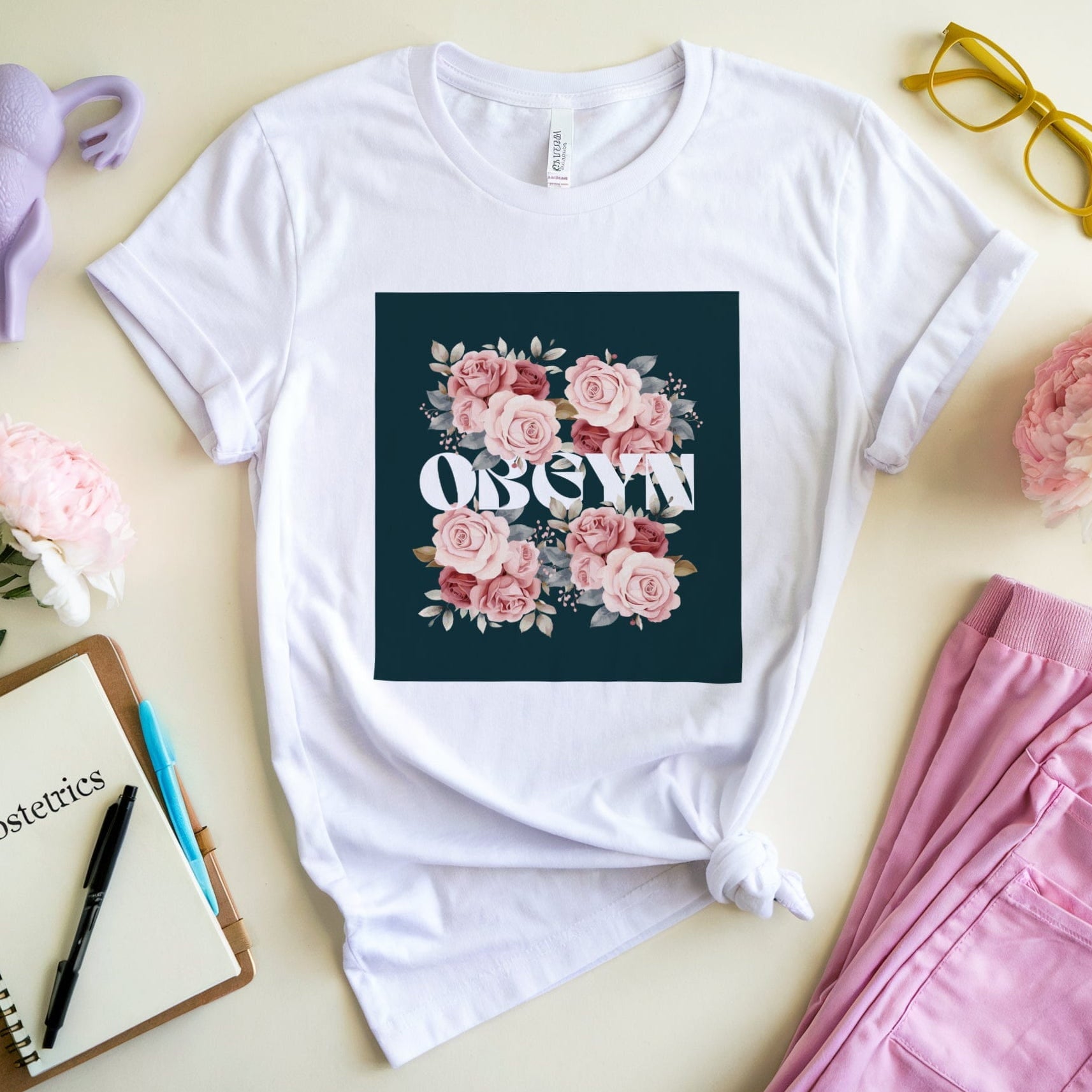 White t-shirt with floral design and text on a light surface with accessories.